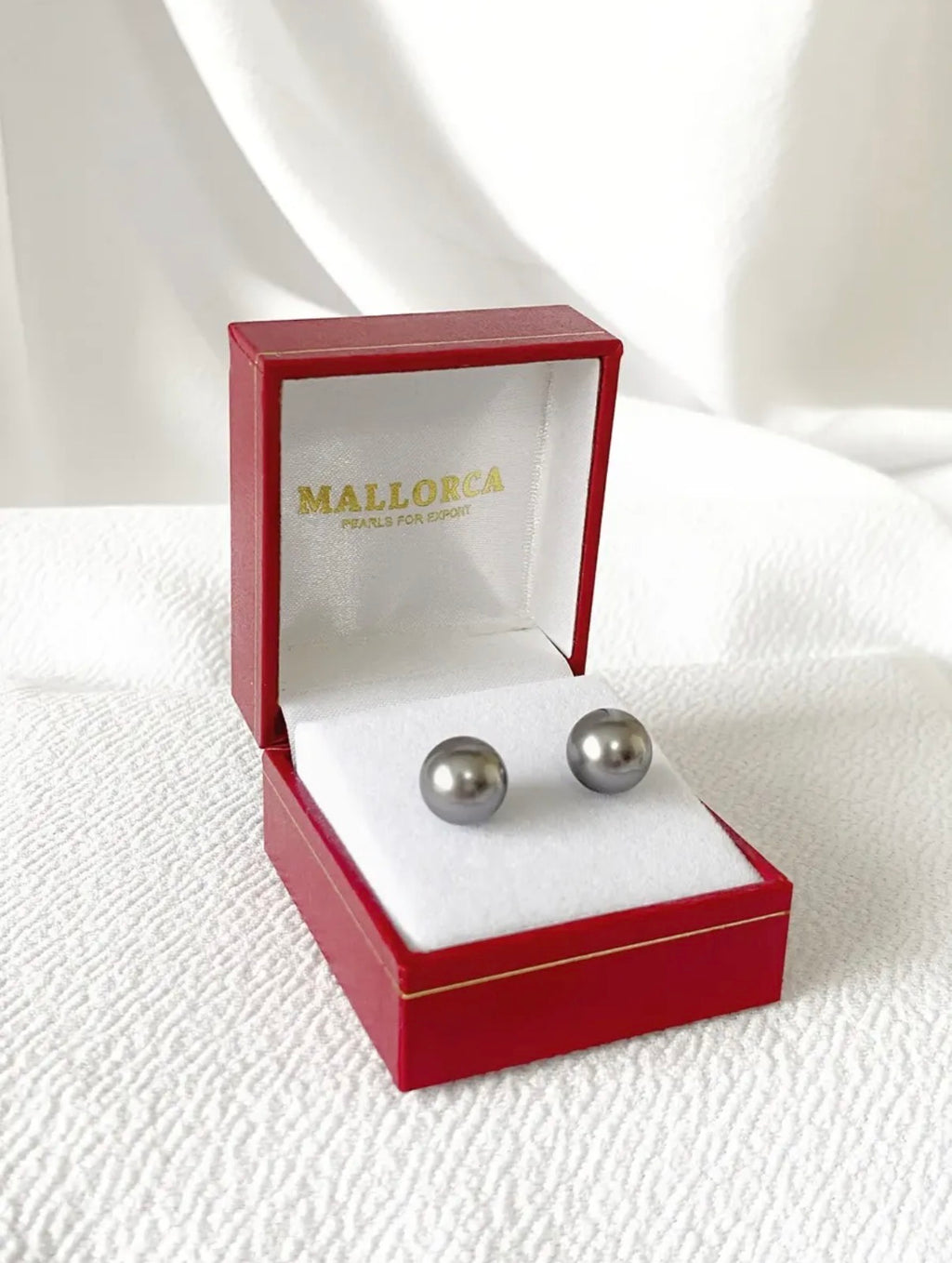 Vista frontal de aros de esfera gris en estuche rojo